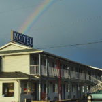 exterior building of the Pacific Inn with a rainbow in the background